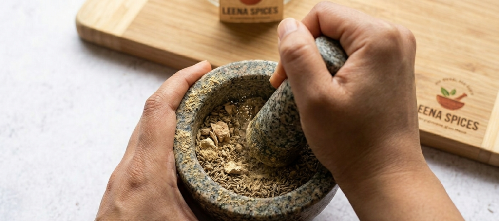 Crushing and grinding birth masala ingredients with mortar and pestle.